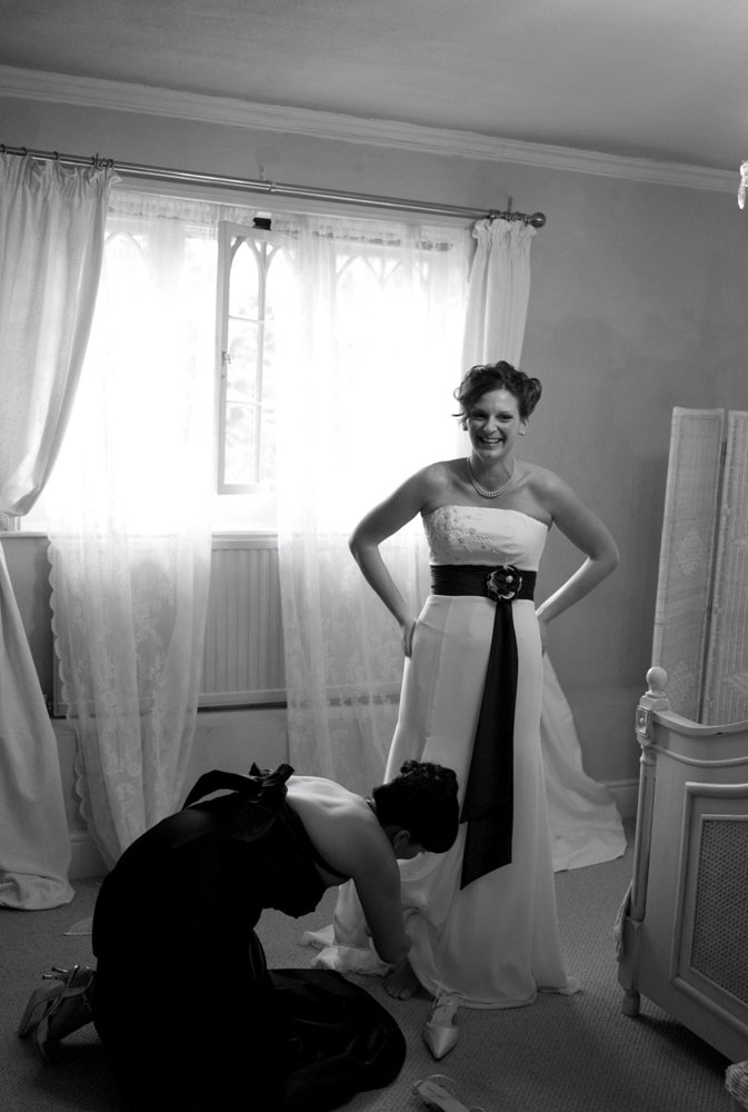 Bride's sister helping with the bride's shoes