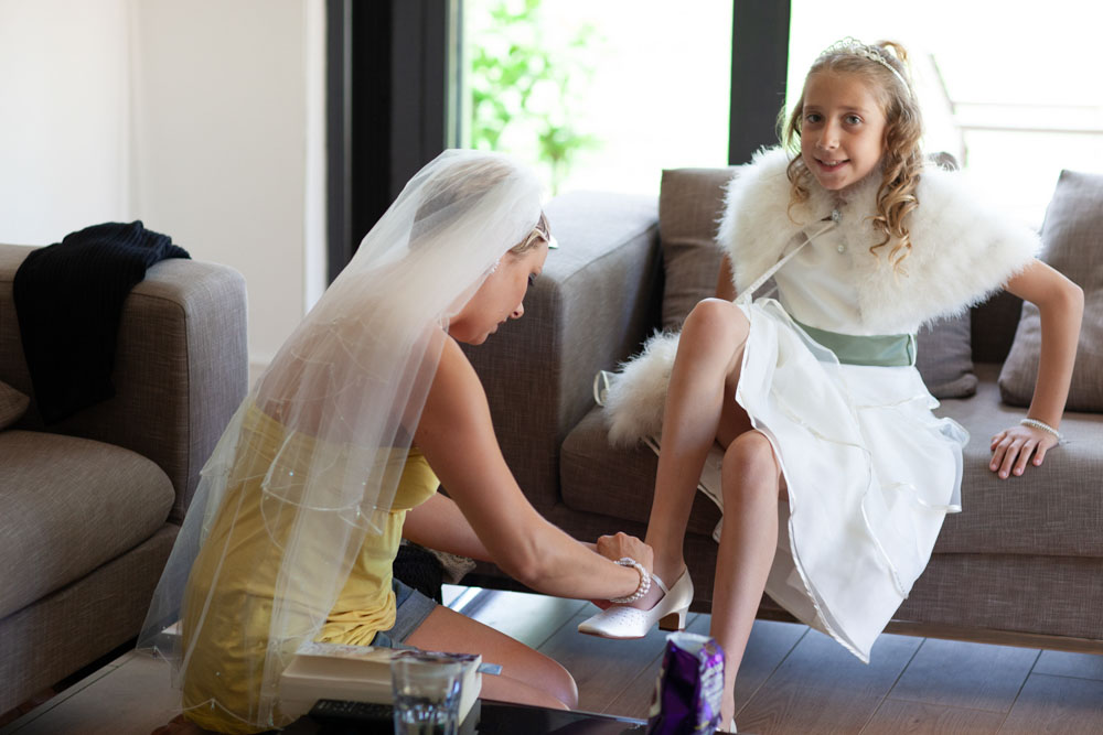 Bride helps bridesmaid with her shoes - KP Club Pocklington wedding photography