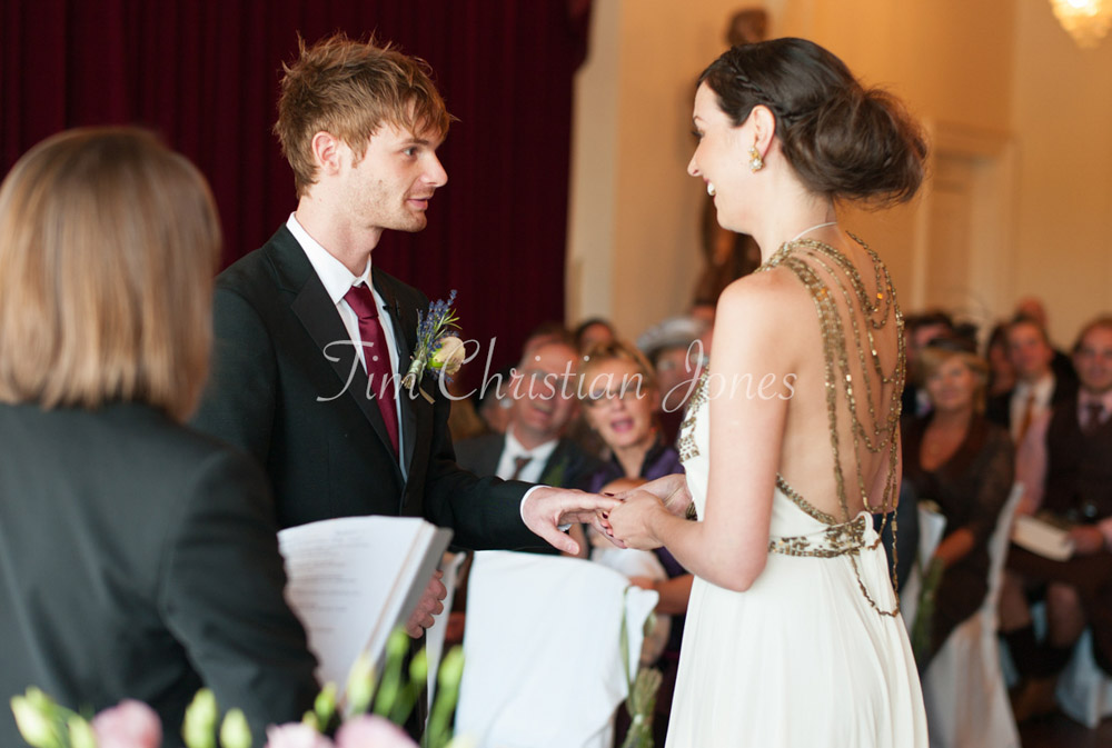 Bride puts on the groom's ring with a big smile