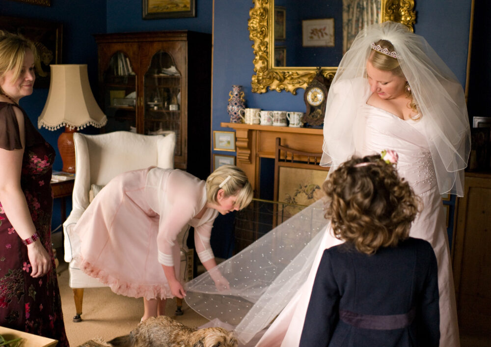 A bridesmaid helps arrange the bride's dress train