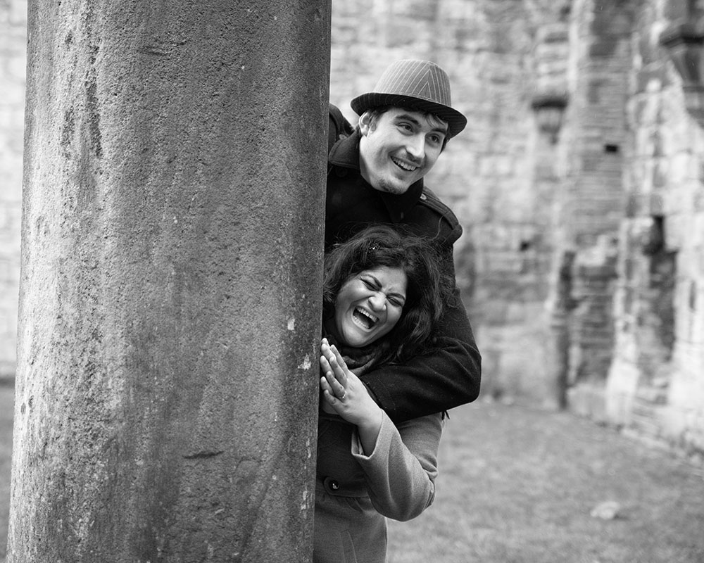 Zehra laughing freely in black and white at Kirkstall Abbey, full of life and fun.
