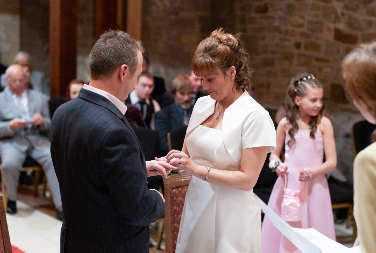 Bride placing the ring on her groom’s finger