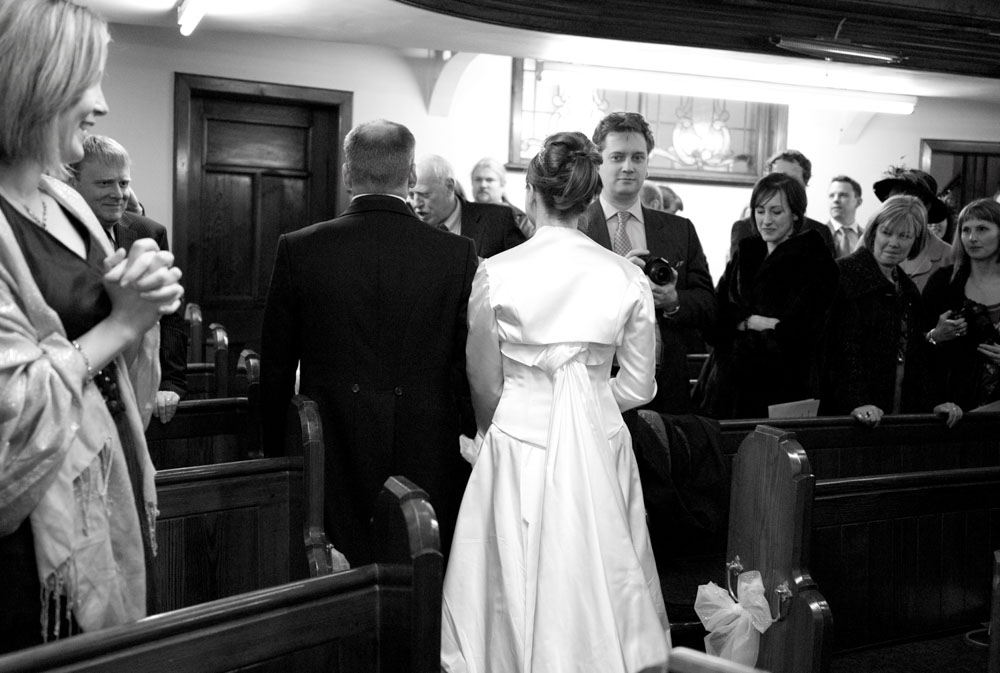 The couple walk out hand in hand through the narrow aisle.