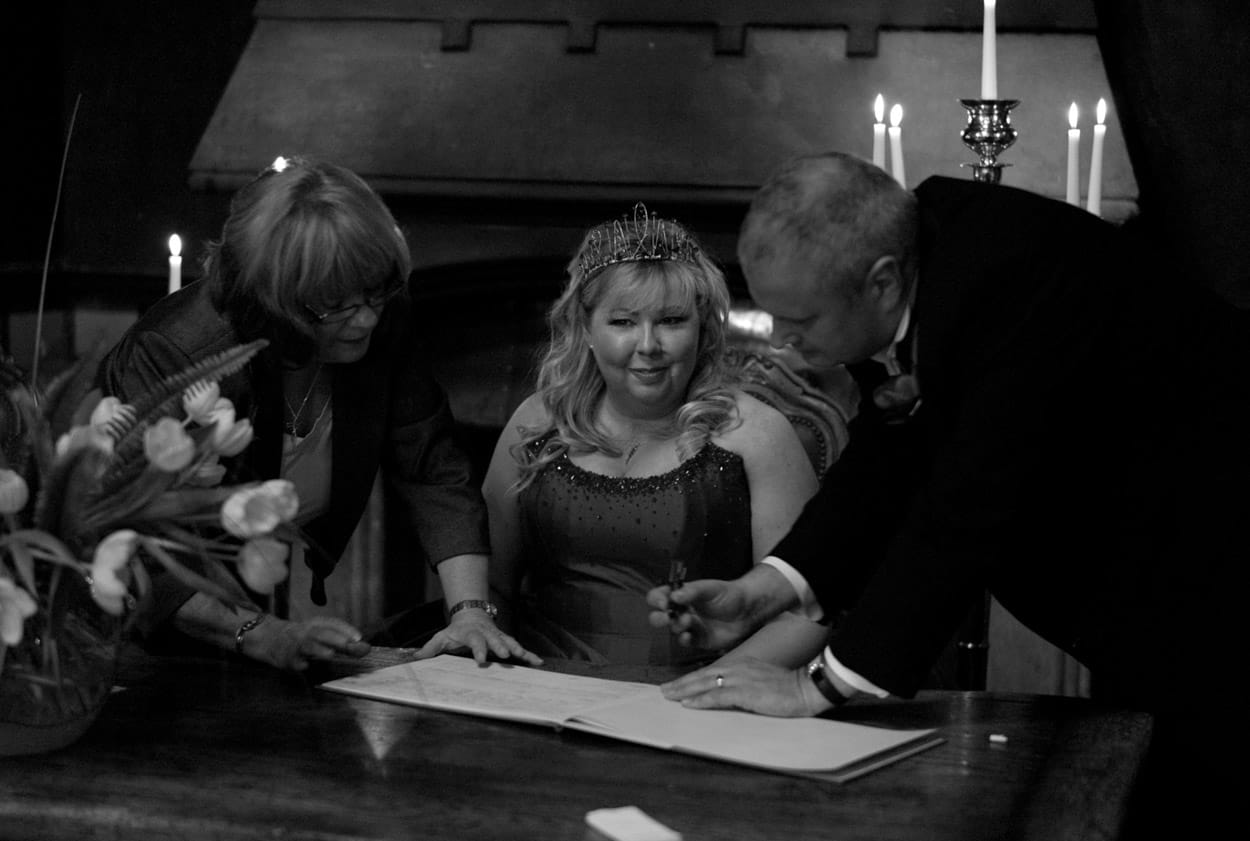 Nikki smiling as she sits to sign the register while Mike signs.