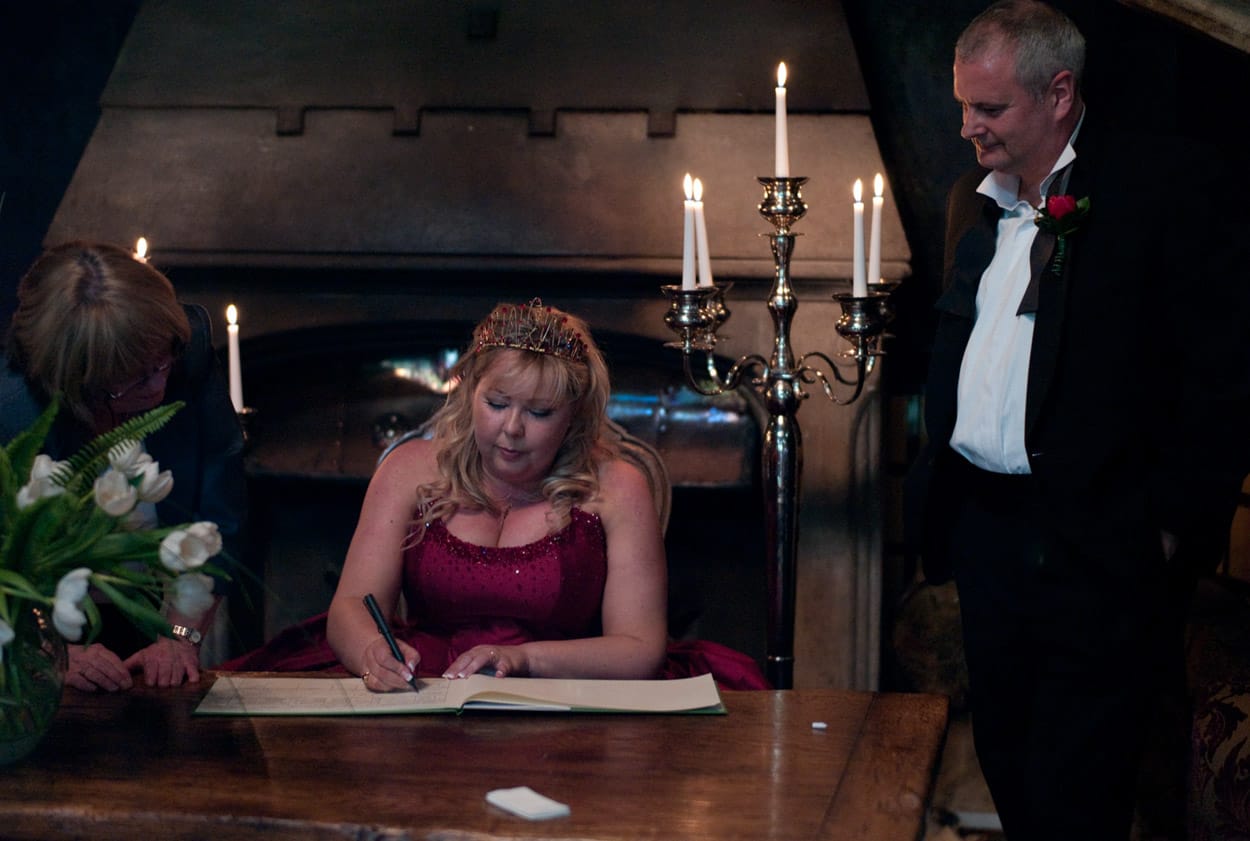 Nikki signs the register beside the fireplace, candles glowing softly.