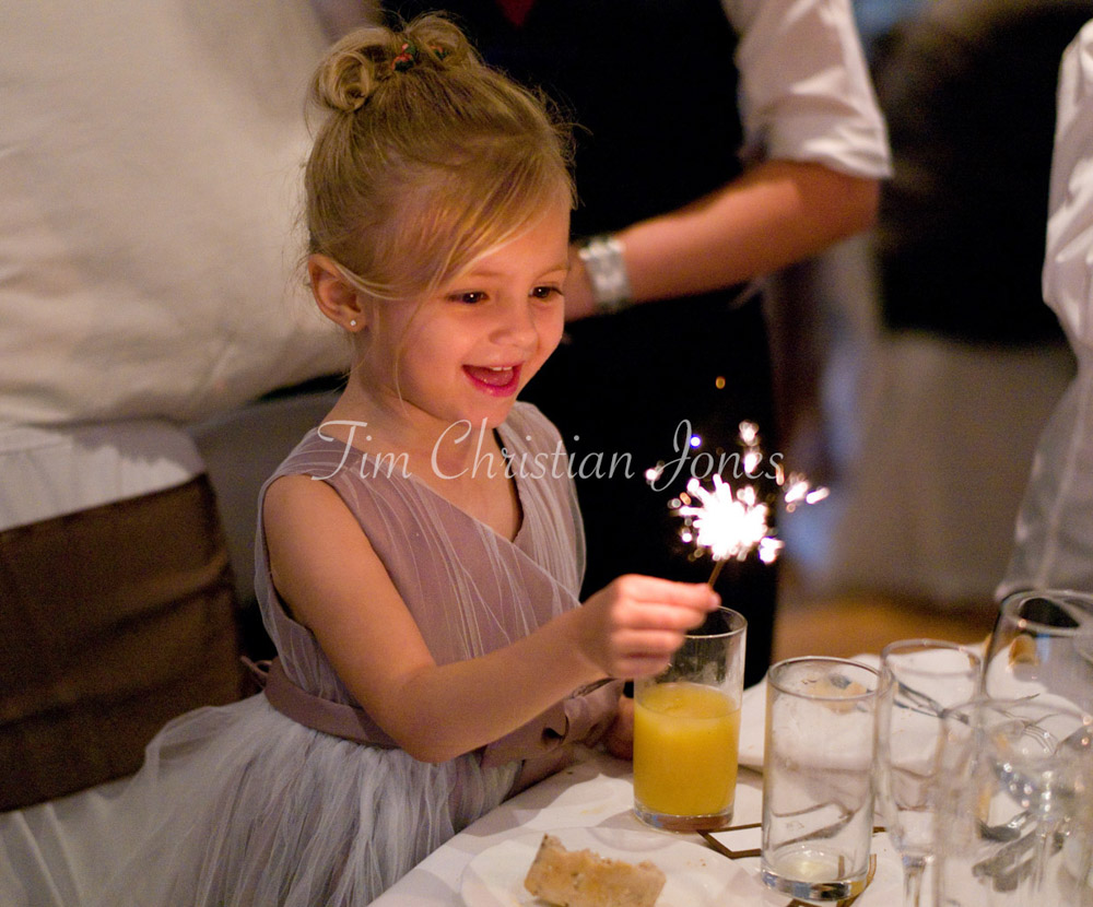 Julie and Pat’s daughter holds a sparkler, her face glowing with delight.