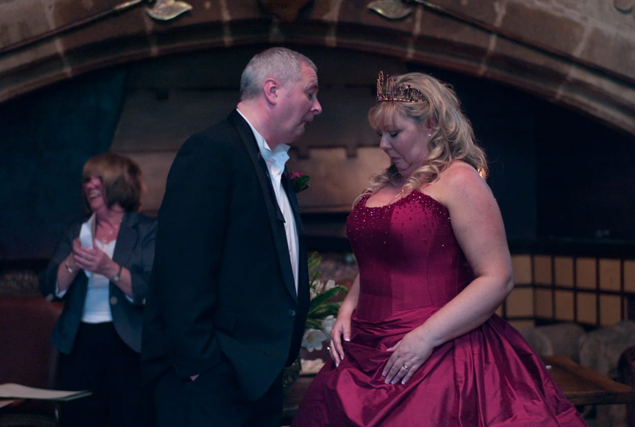 Playful candid of Mike taking a cheeky look down Nikki’s dress front, both laughing.