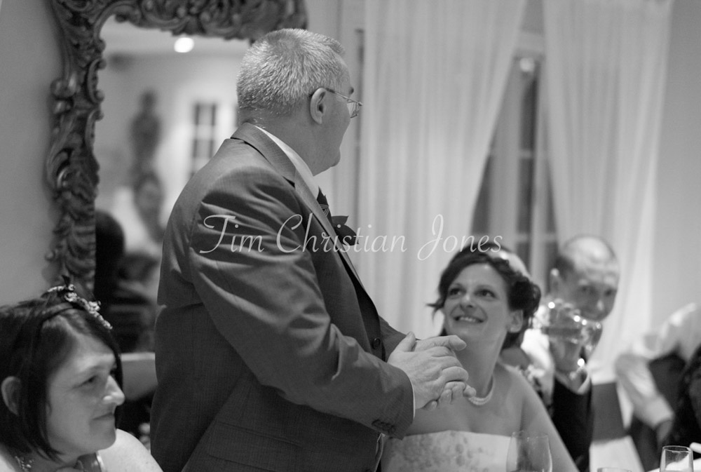 The father of the bride stands to deliver a heartfelt speech, emotion in his eyes.