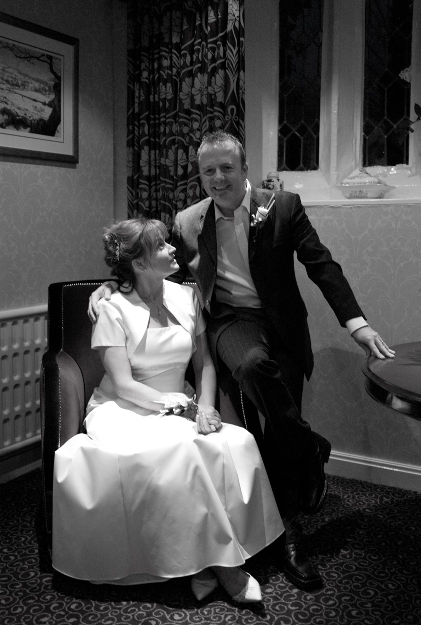 Monochrome portrait of groom smiling as bride looks at him