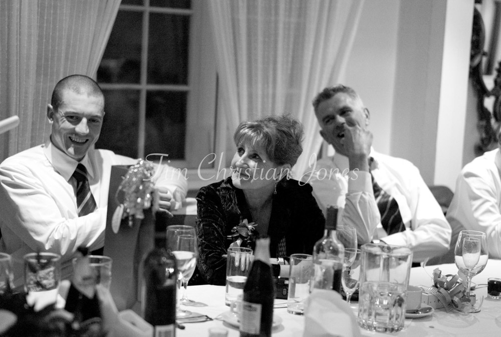 Guests at the top table listen in as the best man prepares to speak, all eyes on him.