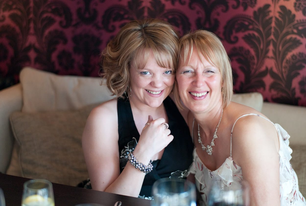 Mother and daughter smiling together at their reception table.