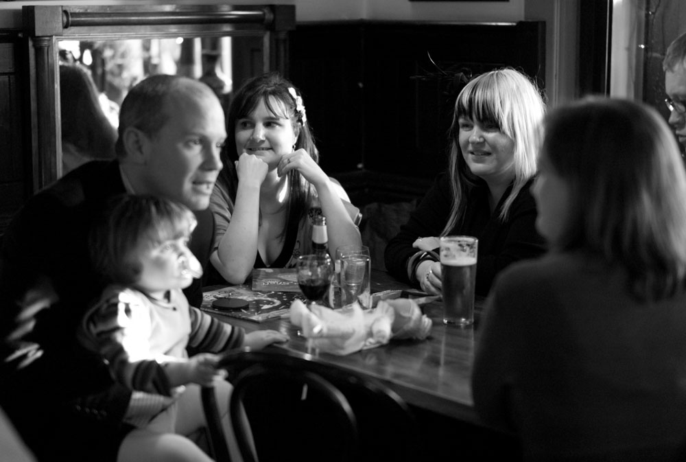 A candid black and white moment of guests enjoying drinks and conversation.