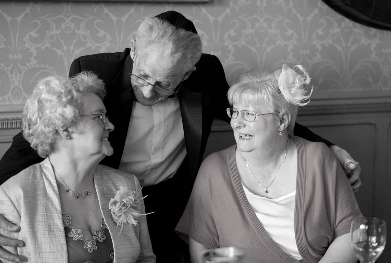 Group shot of friends and family smiling warmly at their table.