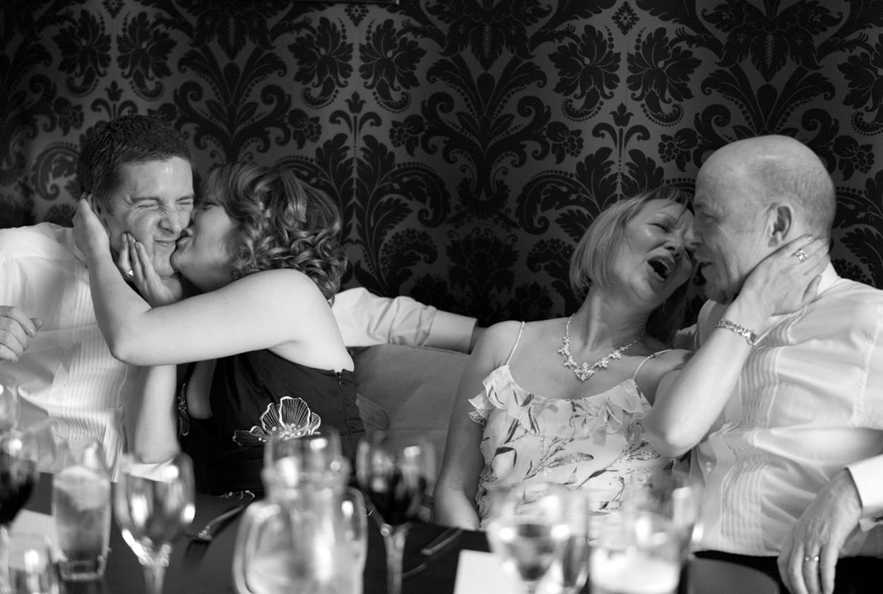 Family table shot with guests giving affectionate kisses.