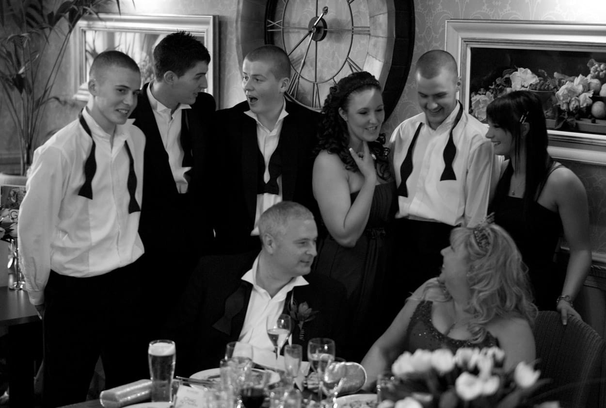 Nikki and Mike chatting with family behind them during a table photo.