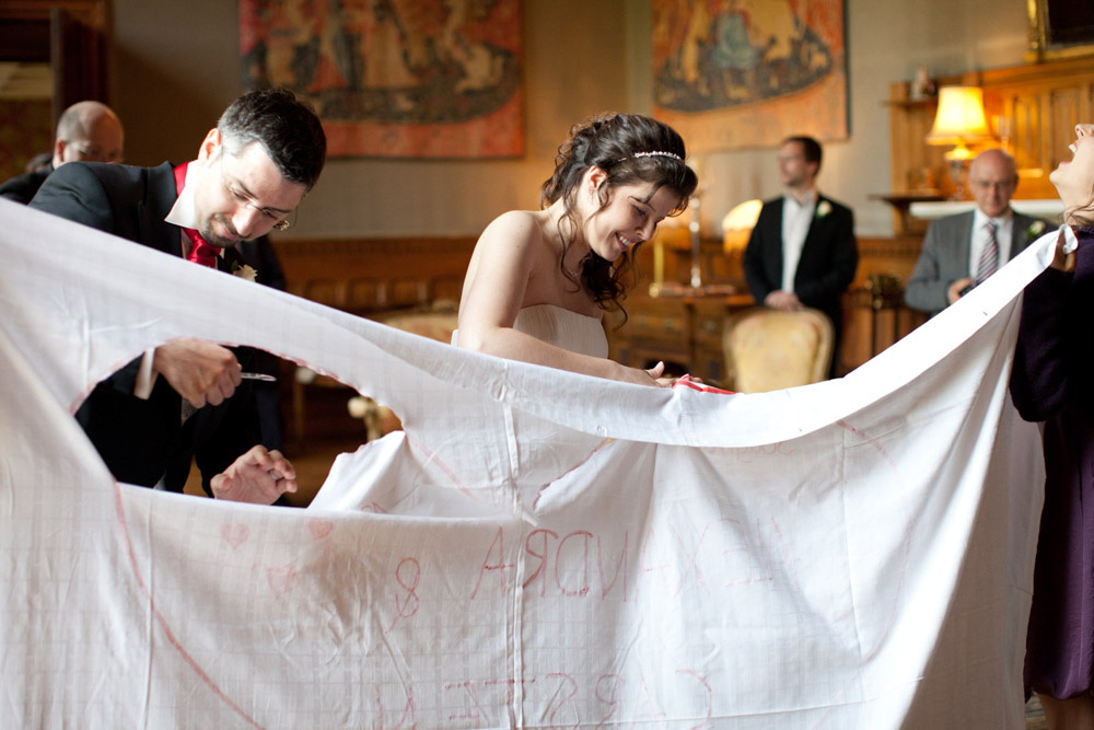 Bride and groom smiling together as they cut through the sheet