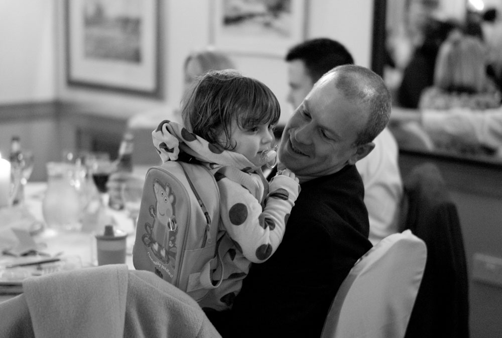 A young boy holds a Peppa Pig backpack as his smiling father stands close by.