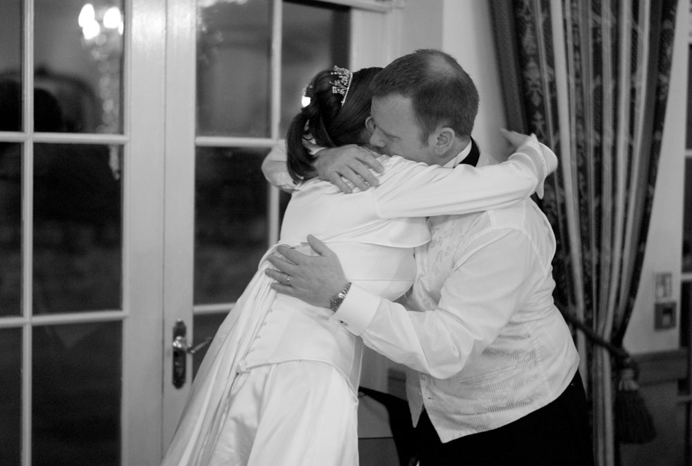 The groom wraps his bride in a warm hug as his speech ends.