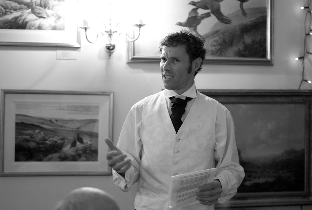 The best man begins his speech, standing confidently as the room listens.