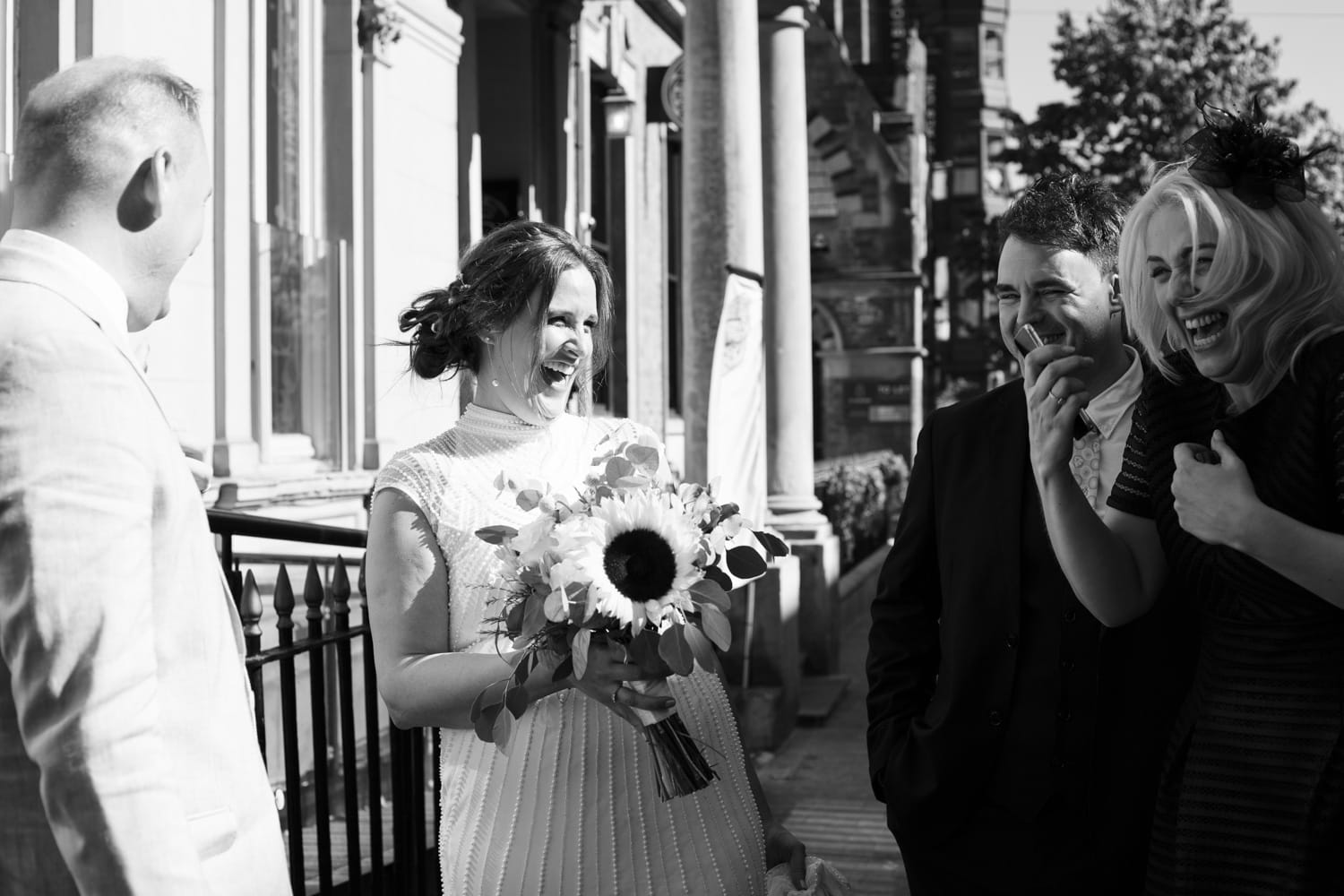 Bride laughing with the groom’s sister outside The Lost & Found after their Leeds Civic Hall ceremony — a relaxed, joyful moment in timeless black and white.
