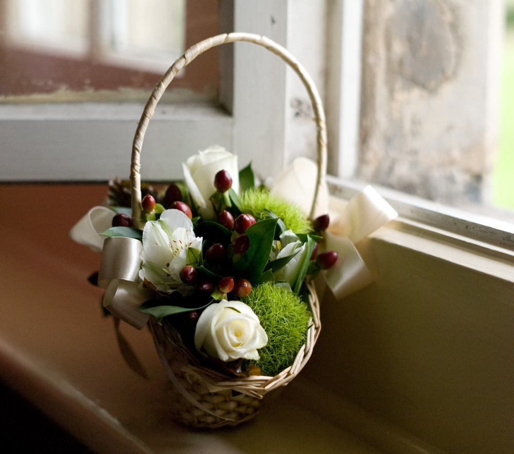 Bridesmaids flower basket on a red windowsill in a rustic Yorkshire wedding venue, captured in soft morning light by a Leeds wedding photographer