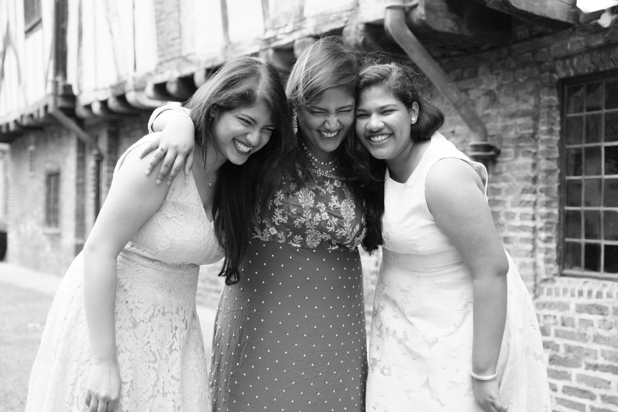 Bride standing between her sisters and bridesmaids as they laugh together during an Asian fusion wedding moment