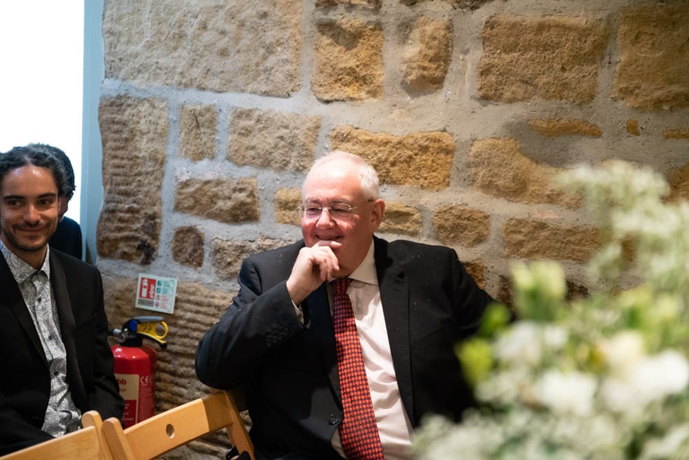 Grandfather smiles warmly while seated before the wedding ceremony begins at the Chilli Barn in Otley.