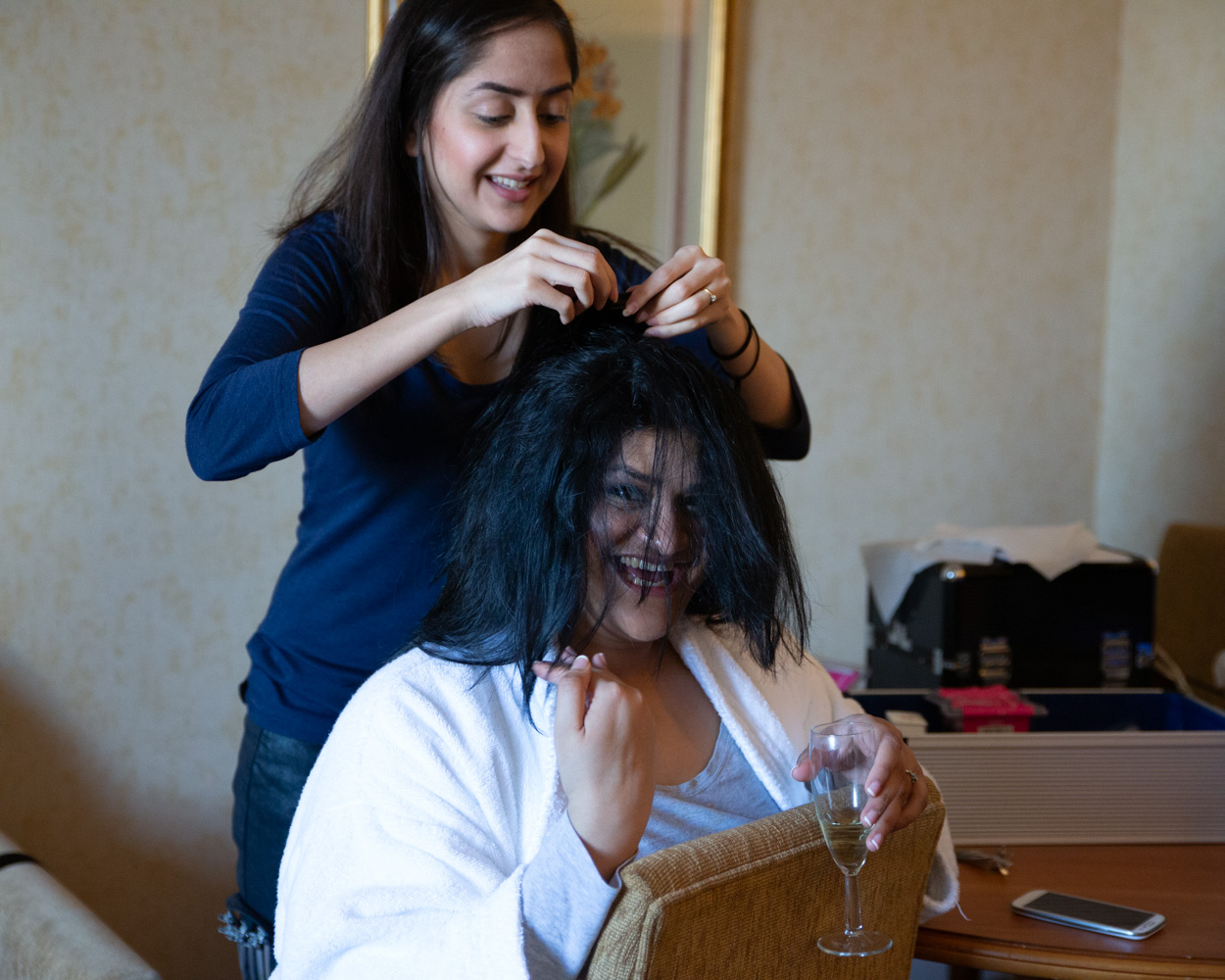 Laughter as Zehra’s hair covers her face mid-styling, the hairdresser grinning beside her with champagne in hand.