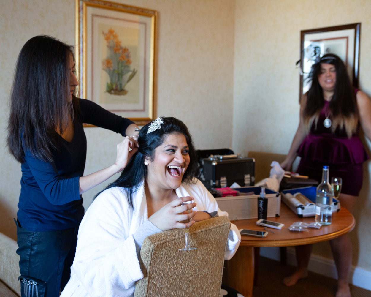 Groomsmen arrive outside the bridal suite with their suits in garment bags, sharing a cheerful hello.
