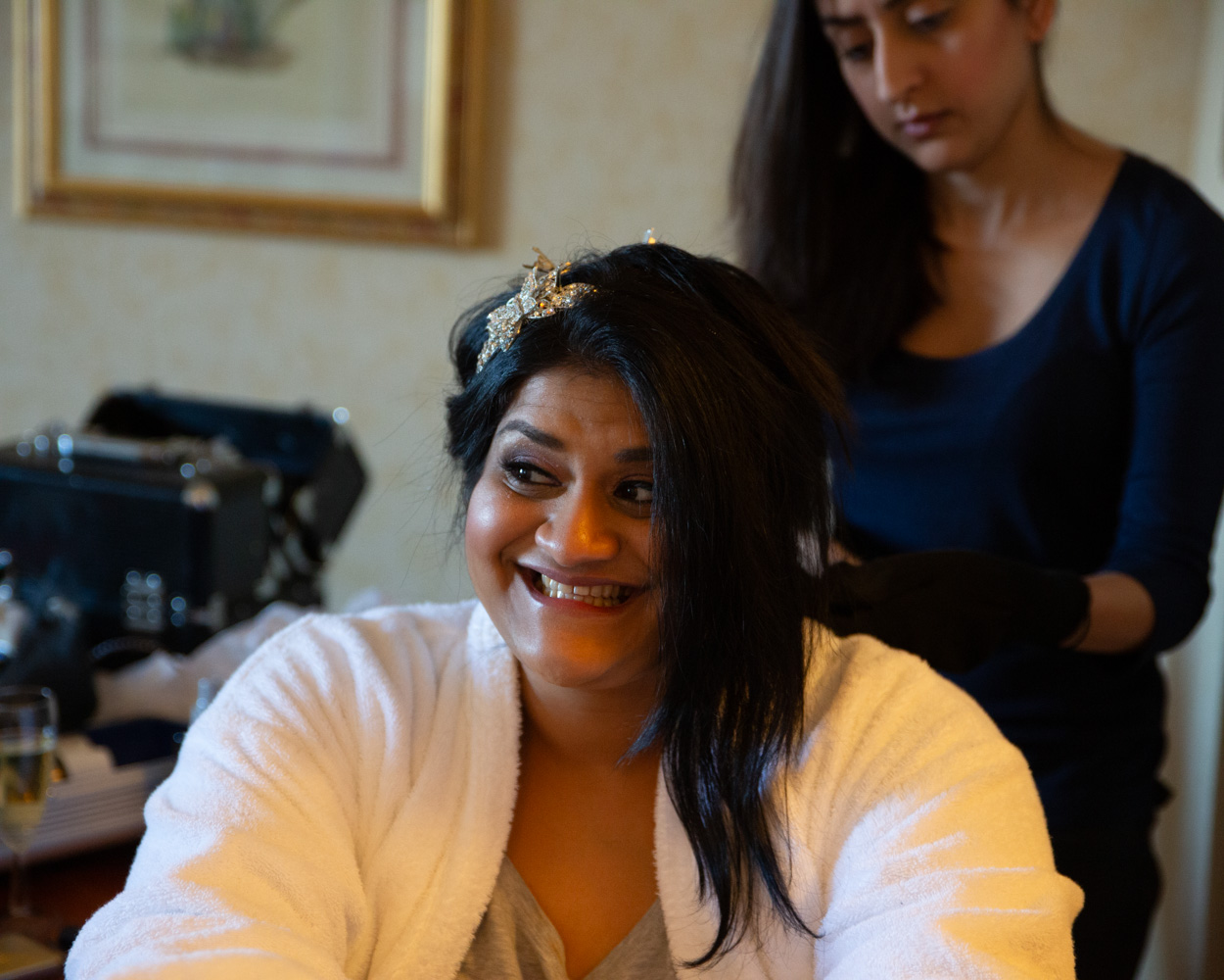 Zehra’s father and mother wait in a side room as her cousin adjusts a cravat with quiet focus.