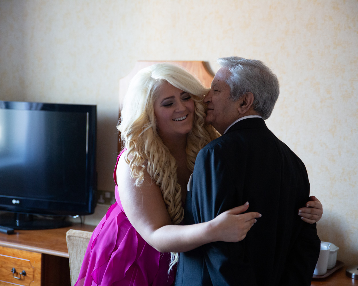 Zehra’s wedding dress hangs in soft light on the bridal suite sofa, captured in timeless black and white in Leeds.