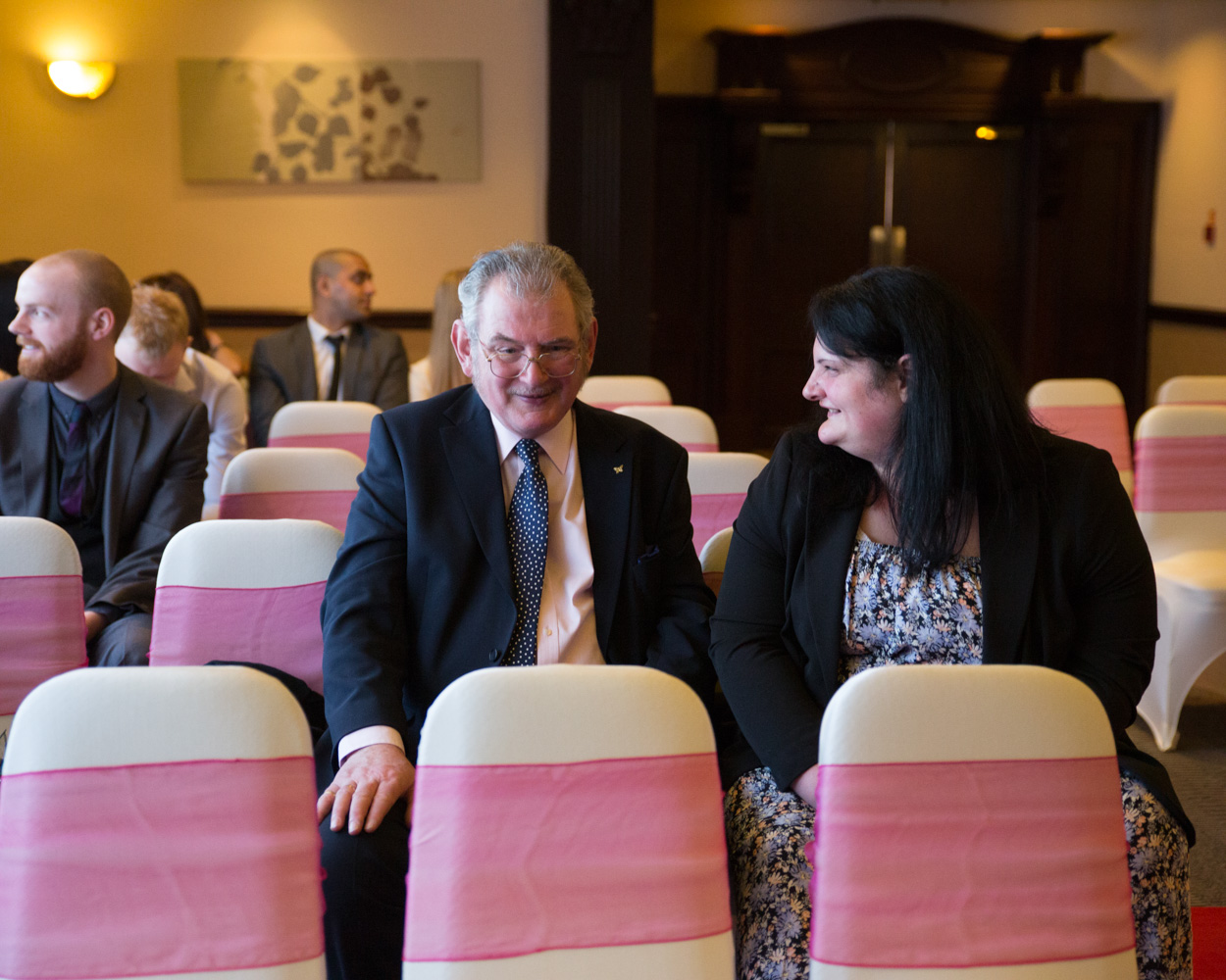 Bride and groom embrace during the ceremony in black and white, sharing a private laugh