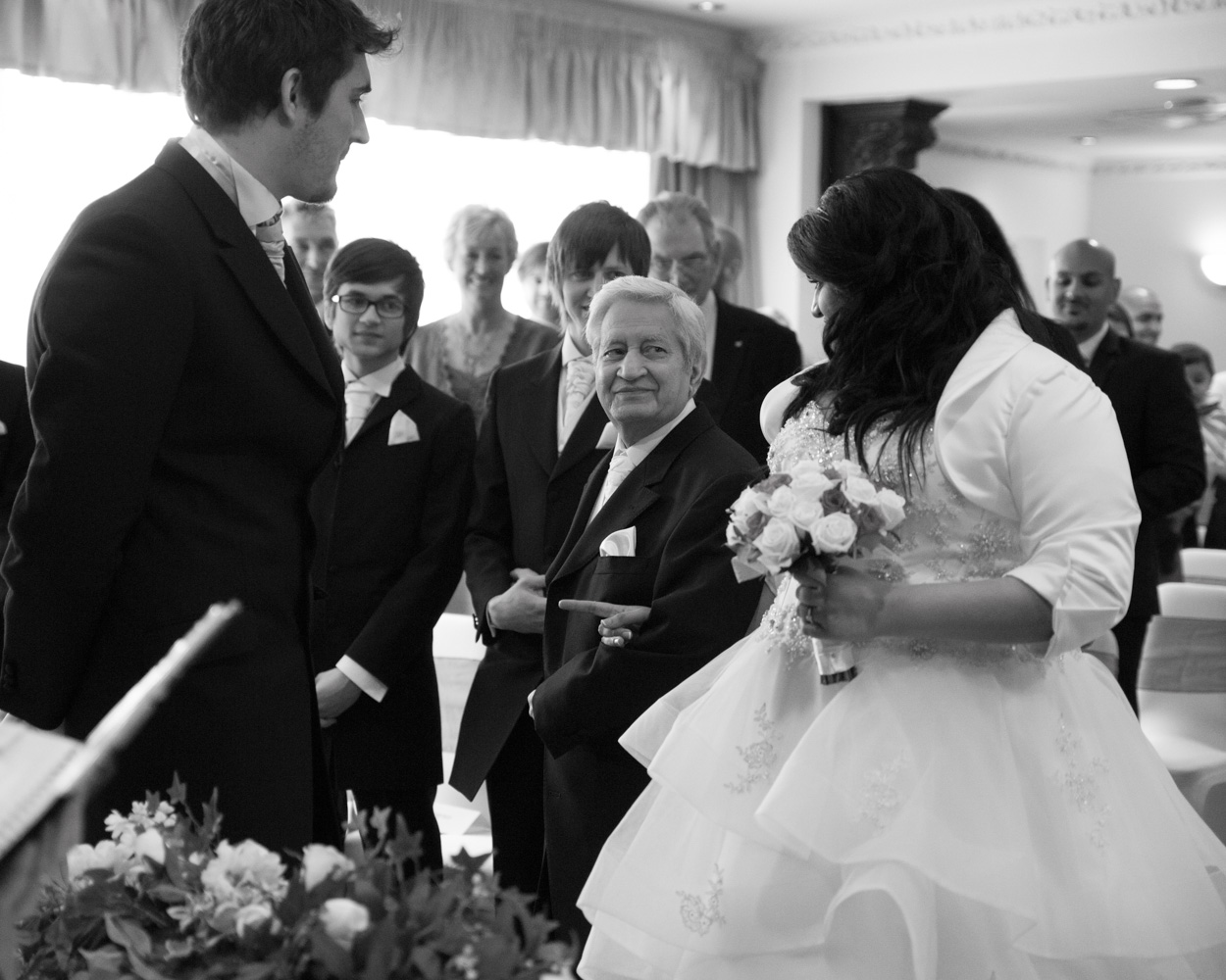 Bride places the wedding ring on groom’s finger, both focused and smiling