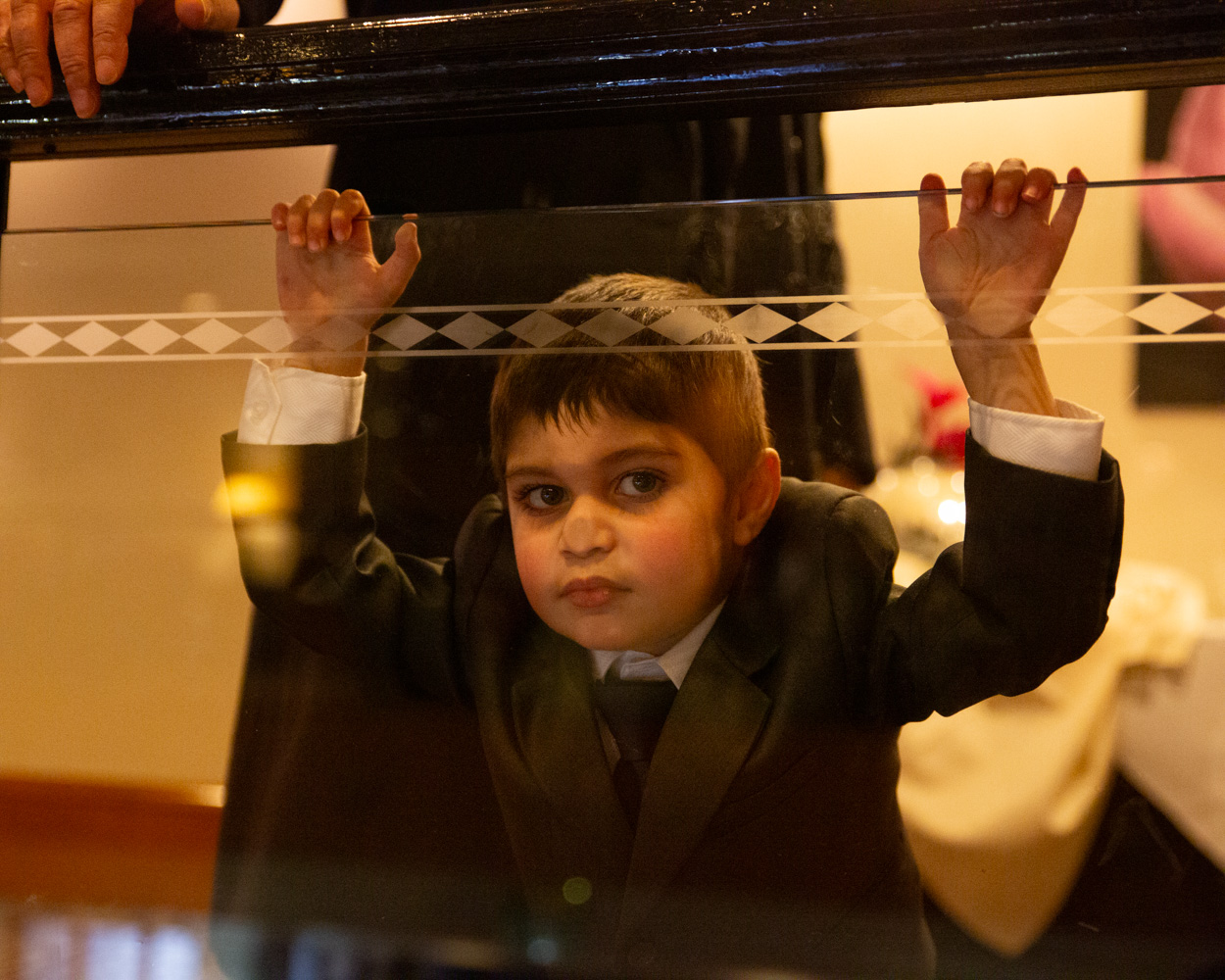 Little boy pressing his face to the glass on Crowne Plaza balcony