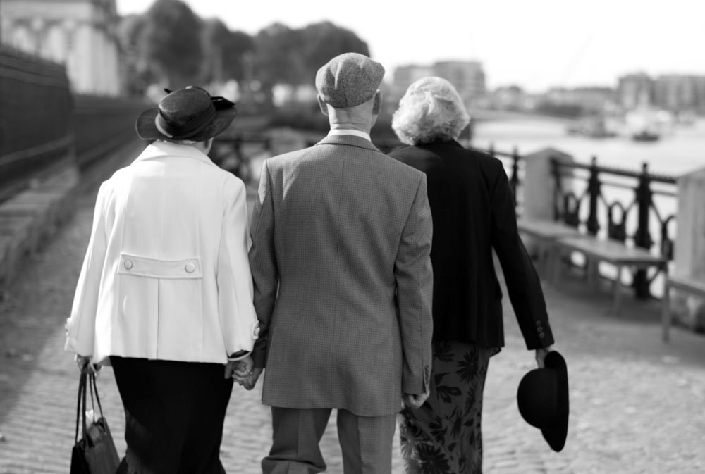 Black and white photo of three elderly guests walking away from the ceremony.