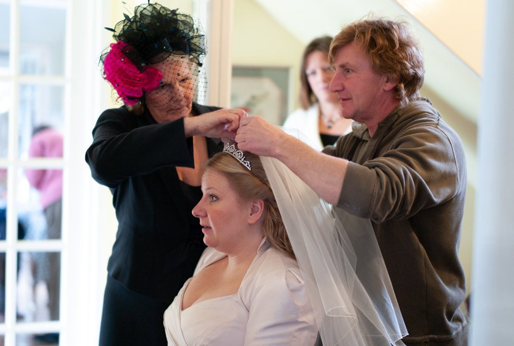 Close moment as family carefully places the bride’s veil.