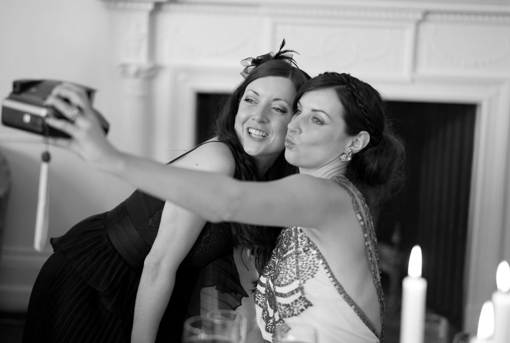Bride pouts for a Polaroid selfie with a close friend on the wedding morning.