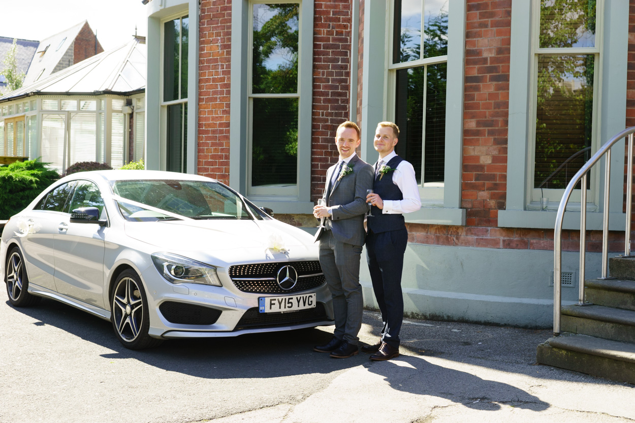 Couple pose with their wedding car