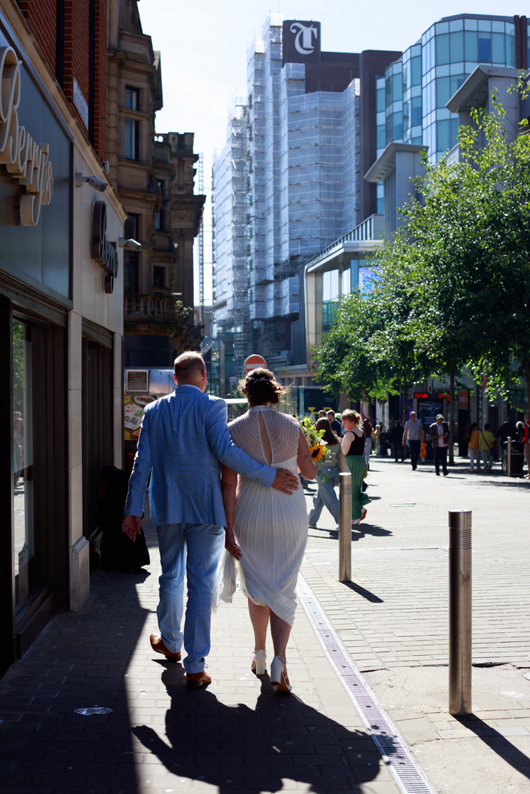 Gemma and Danny walking through Leeds city streets on the way to their wedding reception at Lost & Found, captured as a natural documentary wedding moment