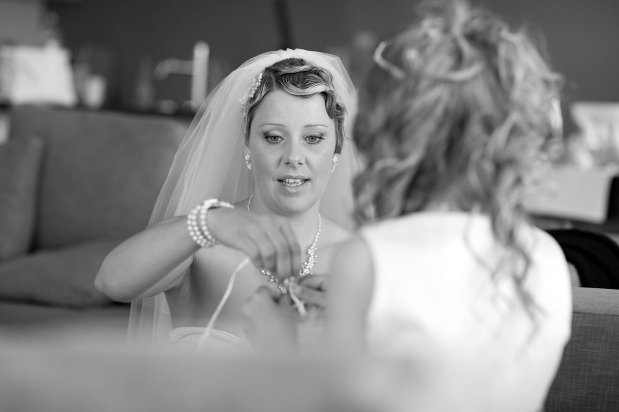 Bride in veil and T-shirt helping her young bridesmaid get ready in the cabin.