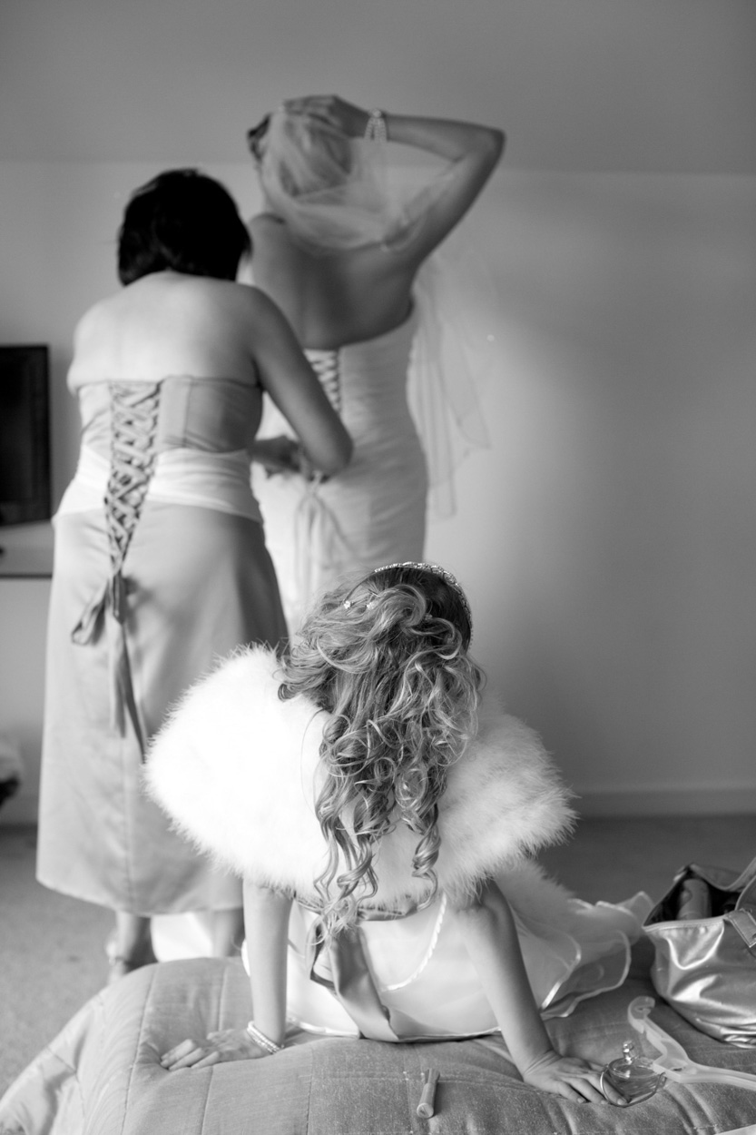 Young bridesmaid sits on the bed watching quietly, black and white.