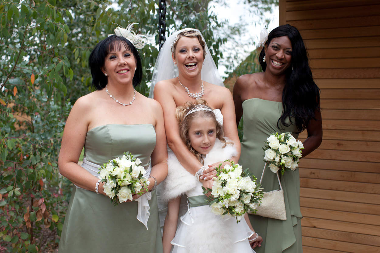 Bride with two bridesmaids and young flower girl, all holding bouquets.