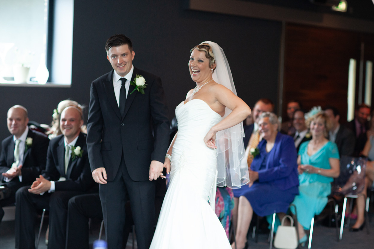 Sam smiles brightly while Tim grins beside her during the ceremony.