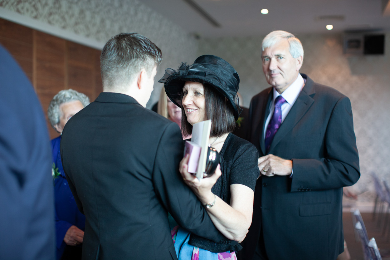 Guests smiling with a wedding photo board in the background.