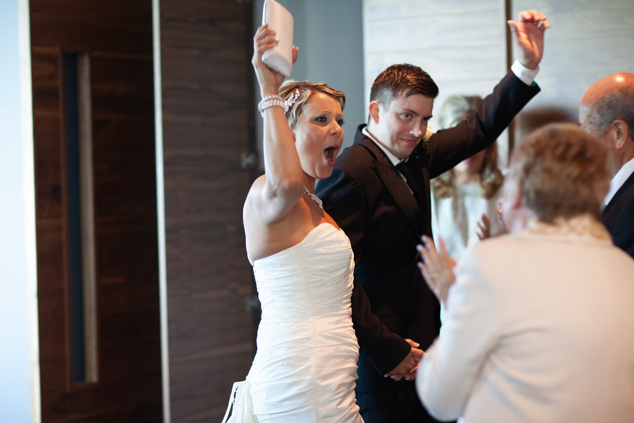 Sam cheers while seated, Tim beside her looking slightly tired but happy.
