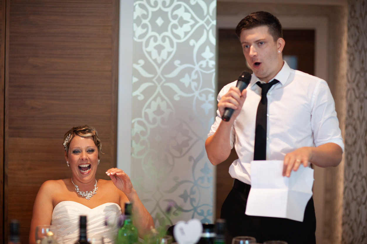 Sam and Tim both grin widely as he continues his heartfelt and funny speech.