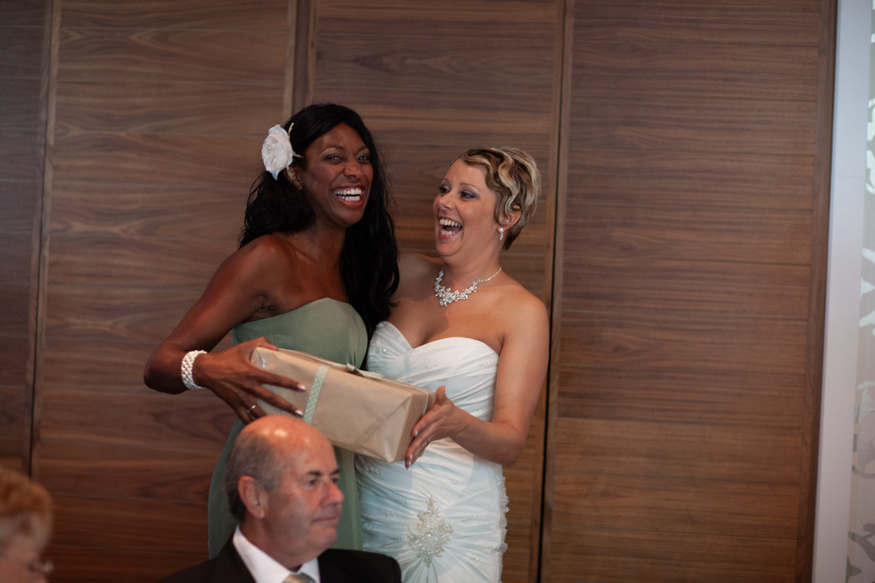 Sam hands a gift to an elderly guest, her expression full of warmth.