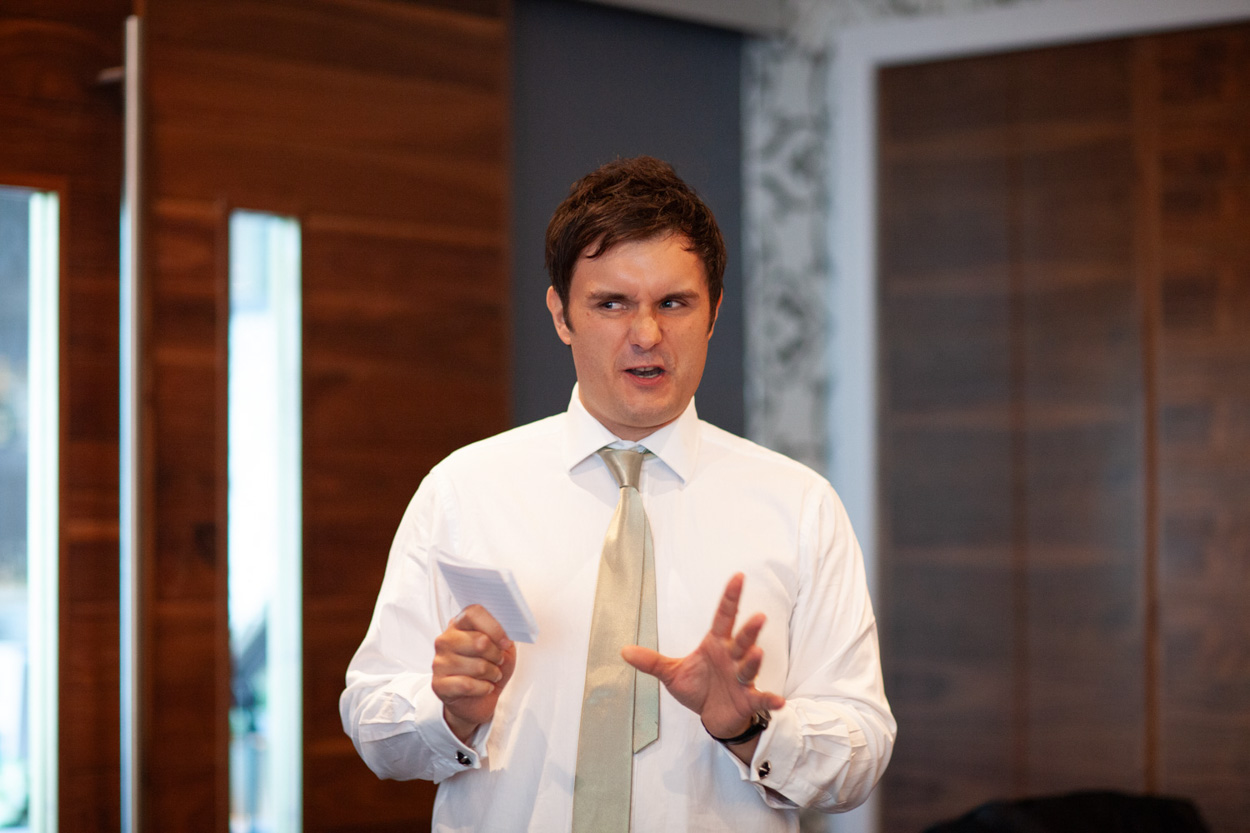 Tim and Sam continue reacting with embarrassed smiles as the second speech reveals more stories.