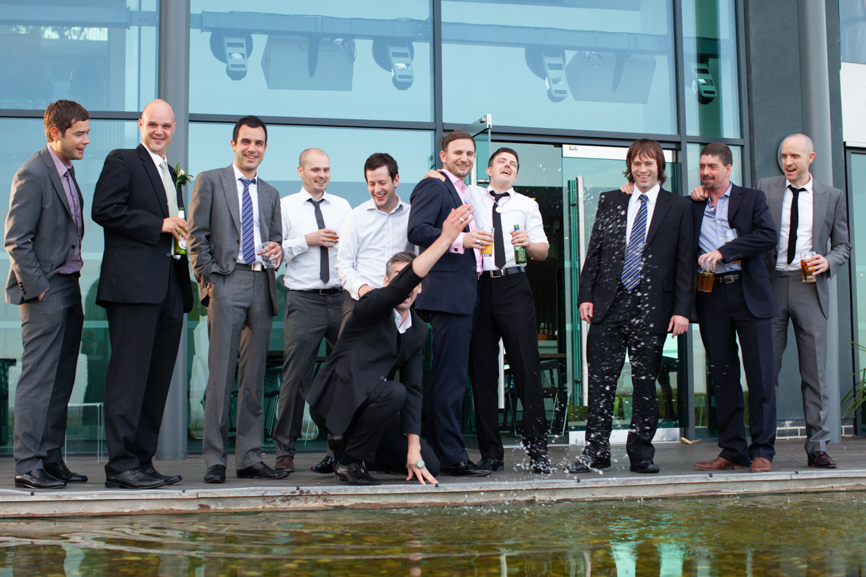 Sam and Tim chat warmly inside the softly lit evening reception room with guests arriving.