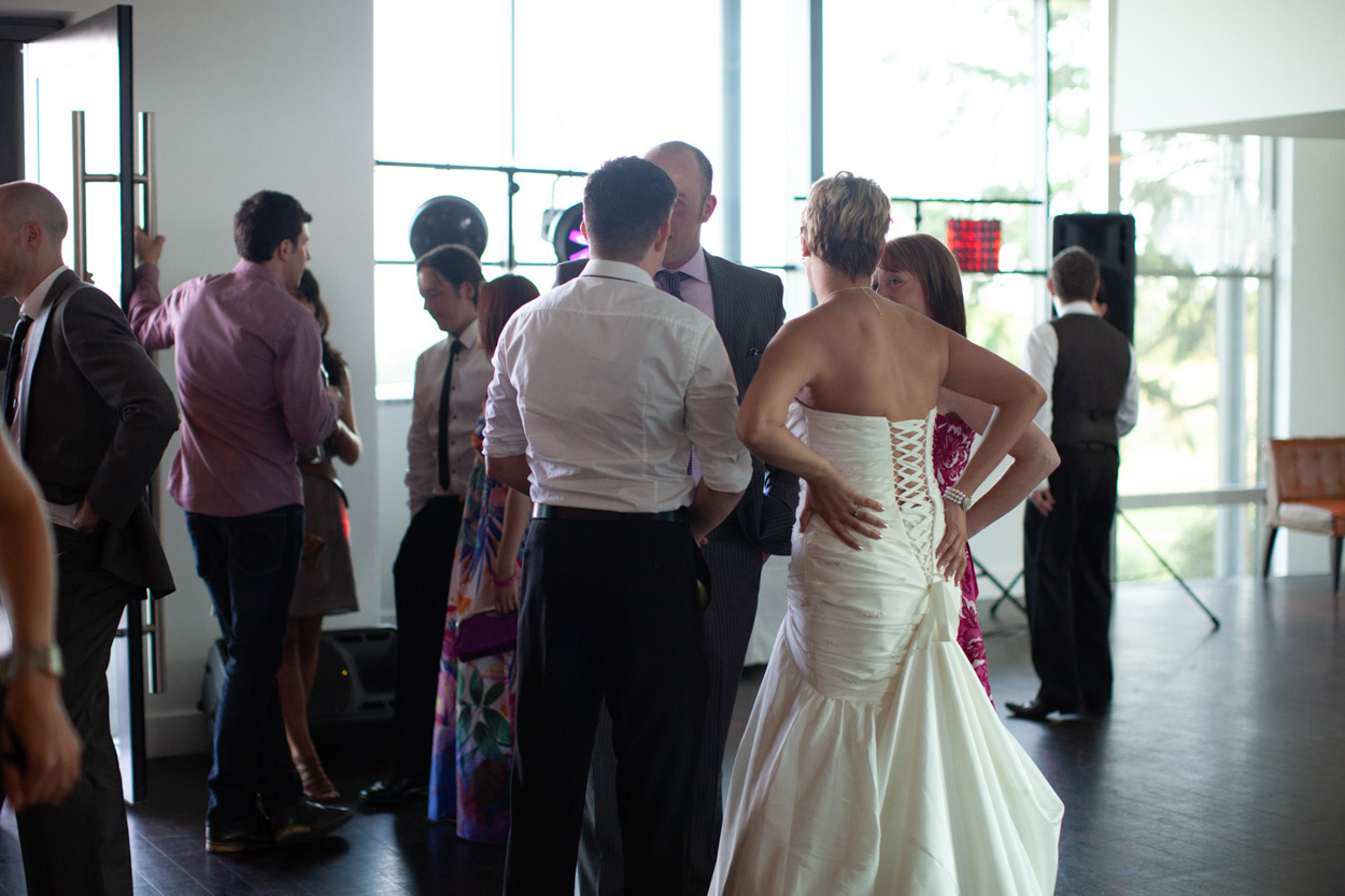Sam and Tim share their first dance surrounded by supportive guests at the edges.